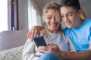 Smiling mother rest with son using smartphone together