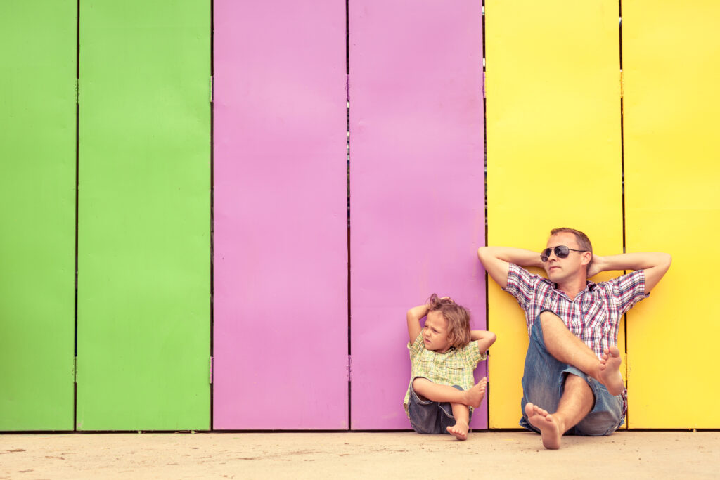 Father and son relaxing in front of a colorful house